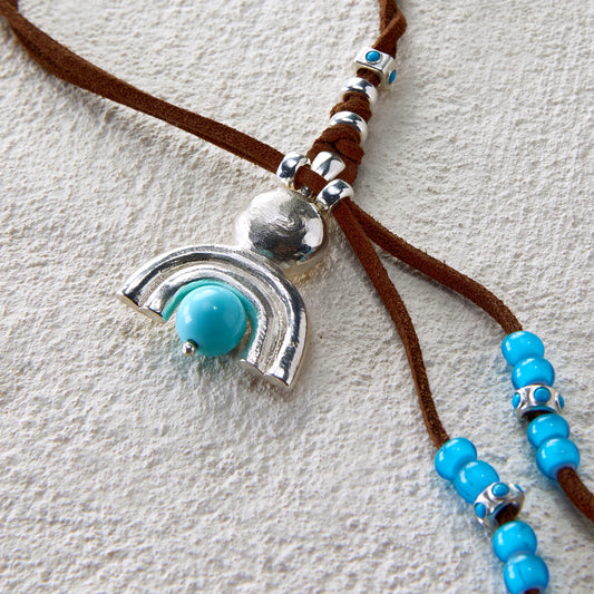 Silver pendant in crescent shape with turquoise bead on leather cord