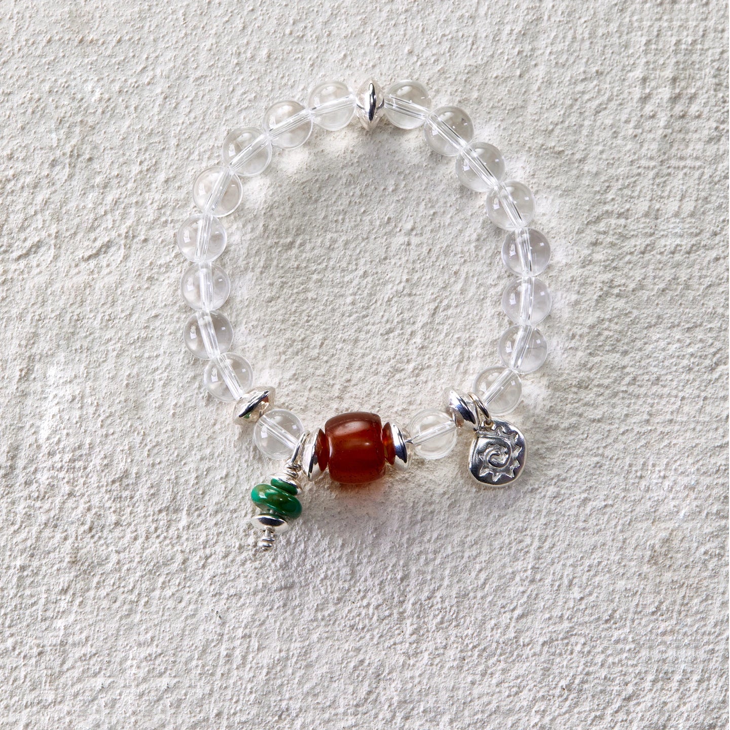 Bracelet featuring clear quartz beads with carnelian and turquoise charms