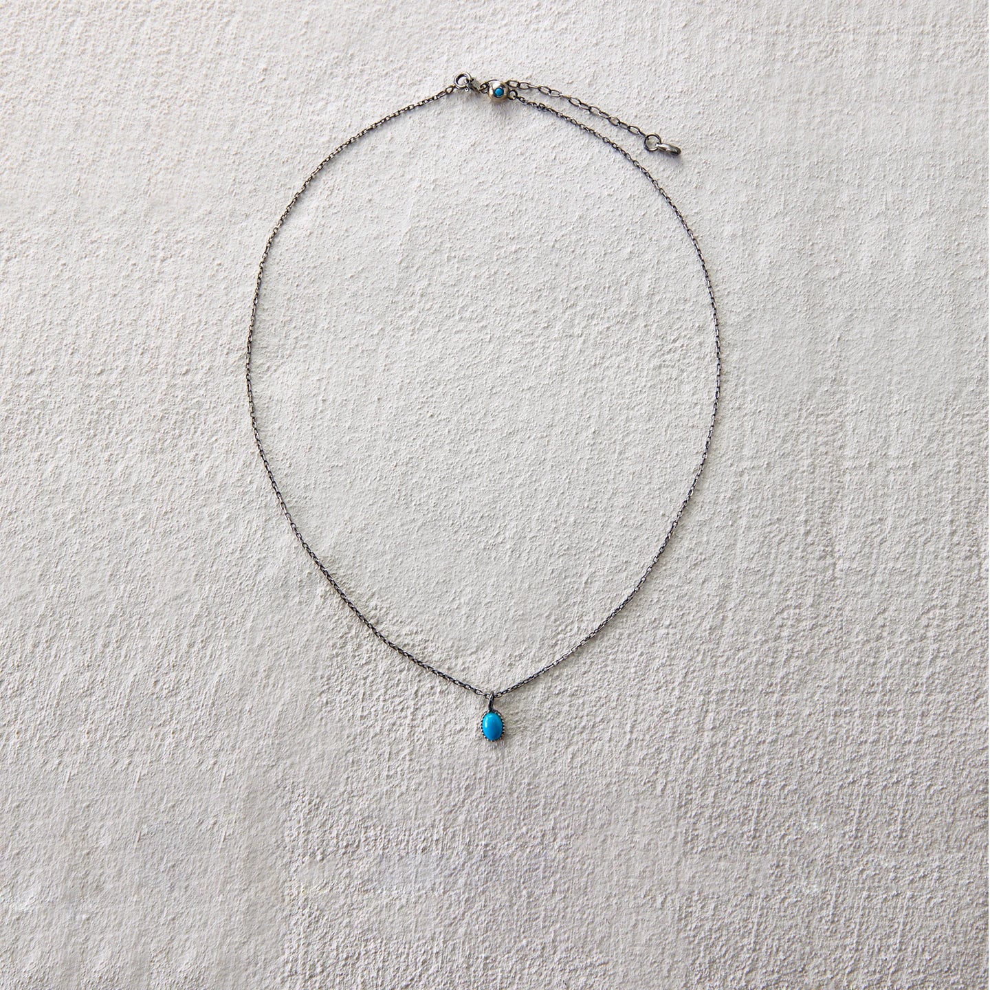 Delicate chain necklace with turquoise teardrop charm, exuding quiet elegance