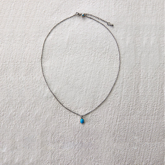 Delicate chain necklace with turquoise teardrop charm, exuding quiet elegance