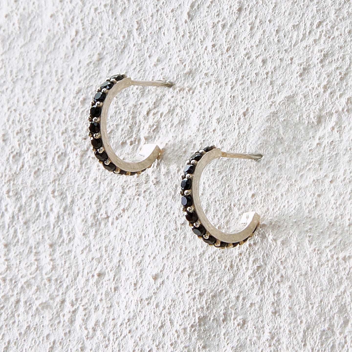 Small silver arc hoop earrings inlaid with black onyx for a sleek and mysterious tone