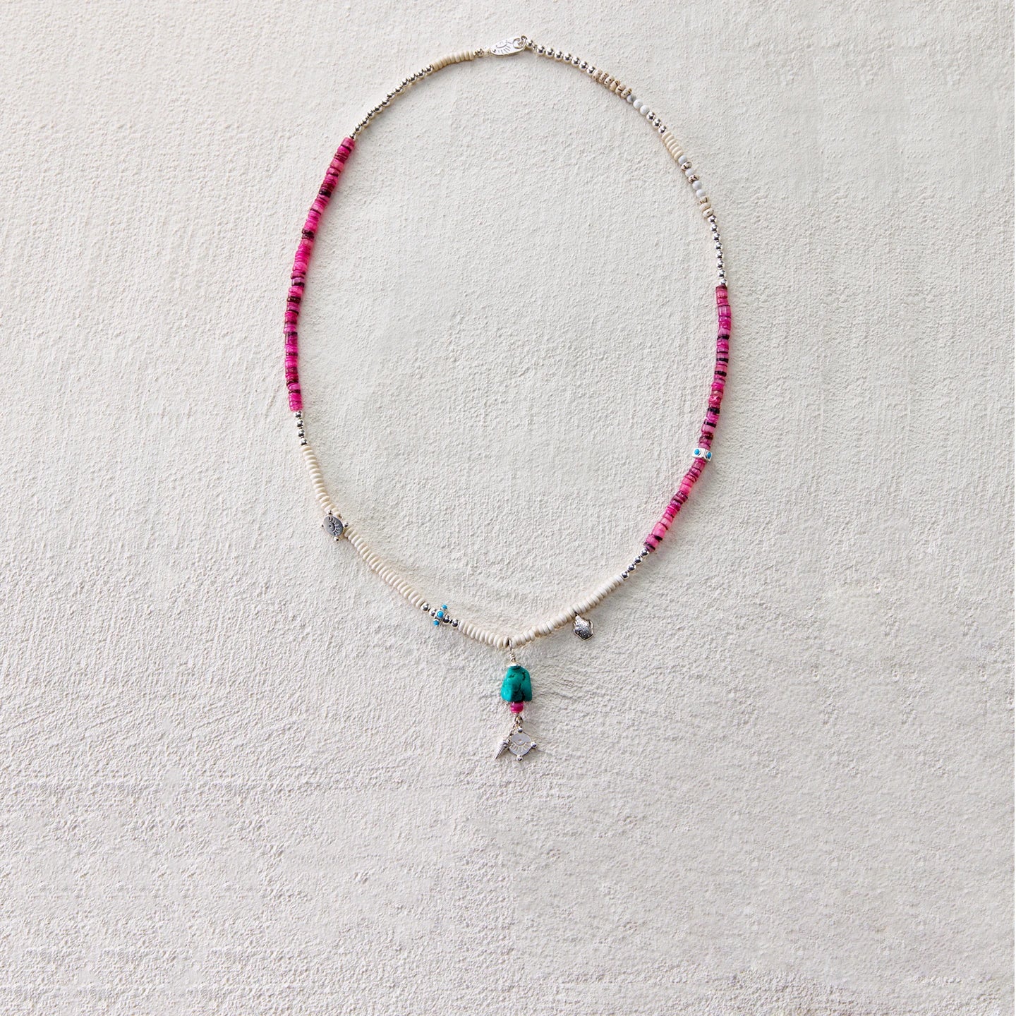 A tribal-style necklace featuring dyed shell and turquoise, symbolizing freedom and wishes