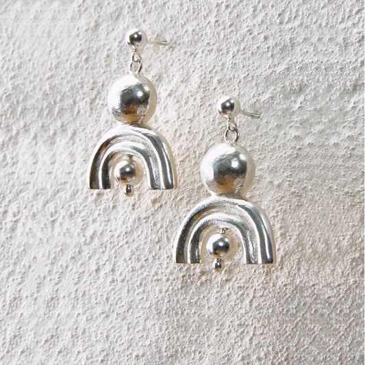 Shiny silver arc earrings with ball details, symbolizing radiance and protection