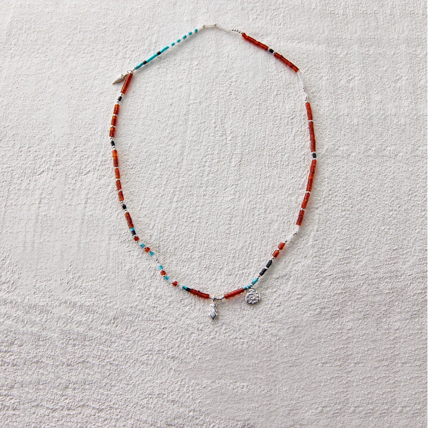 Beaded necklace made of red agate, turquoise, and white jade, adorned with star and coin-like charms