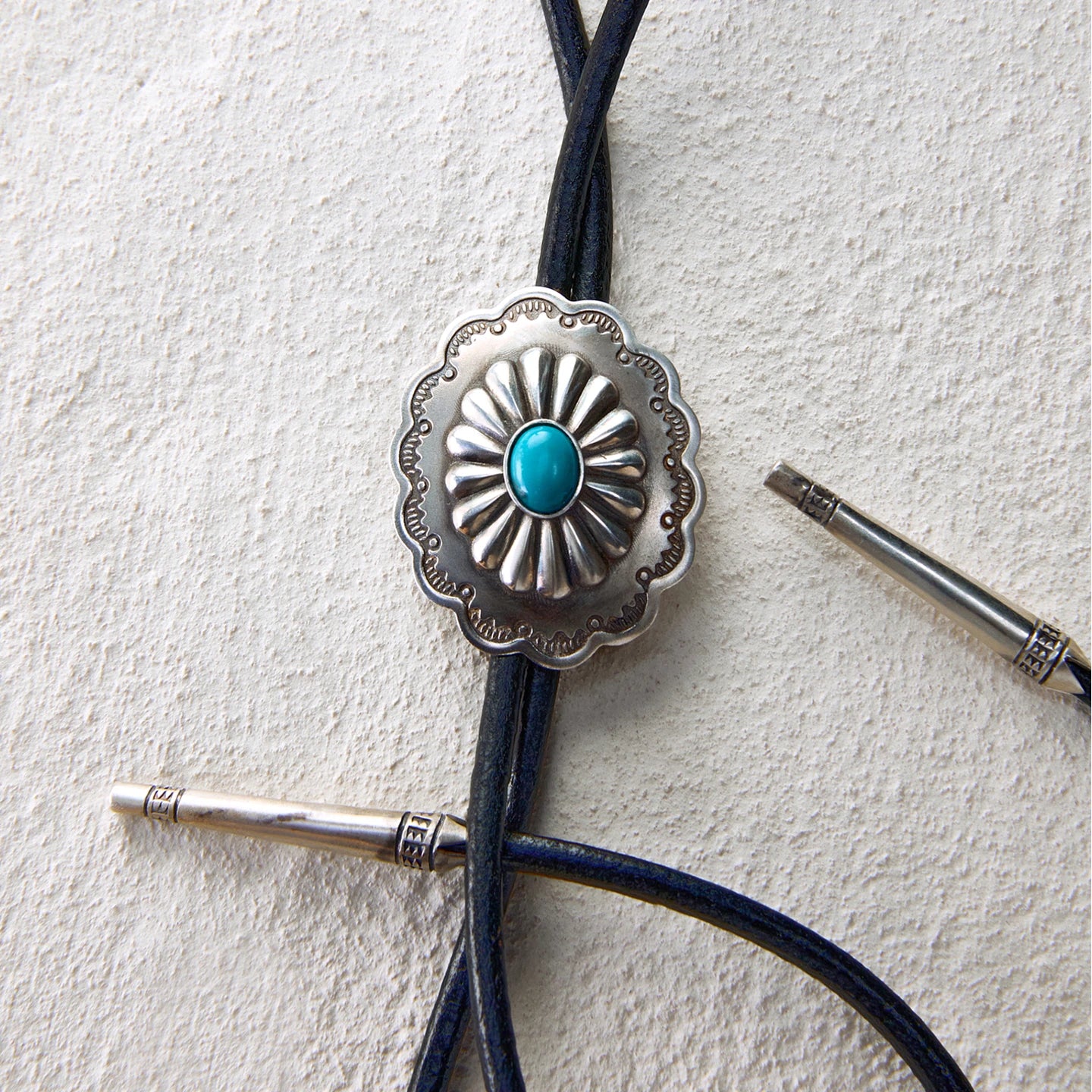 Western bolo tie with turquoise-inlaid floral concho and leather cord