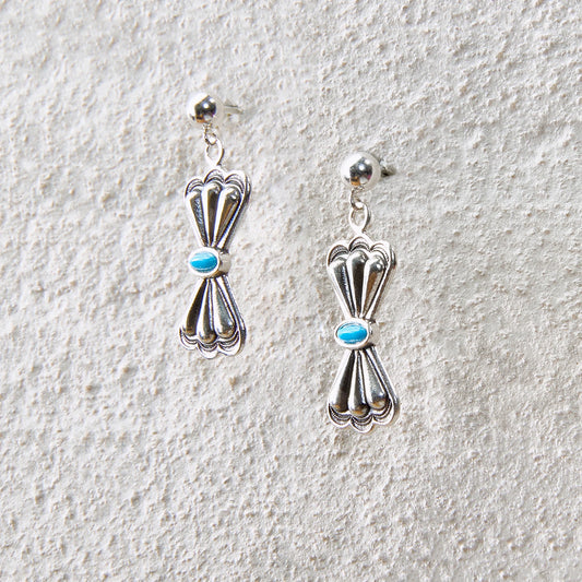 Bow-knot shaped drop earrings with turquoise accent, balancing elegance and strength