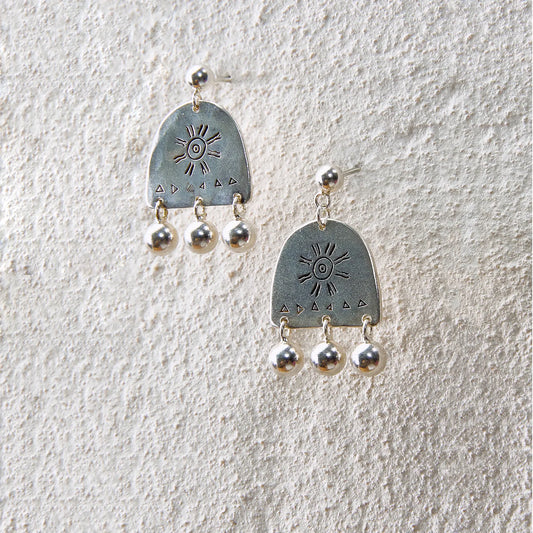 Silver arc-shaped earrings engraved with a sun motif and three dangling beads, evoking light and sound