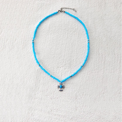 Blue glass beaded necklace with cross-shaped pendant, blending grace and mystique
