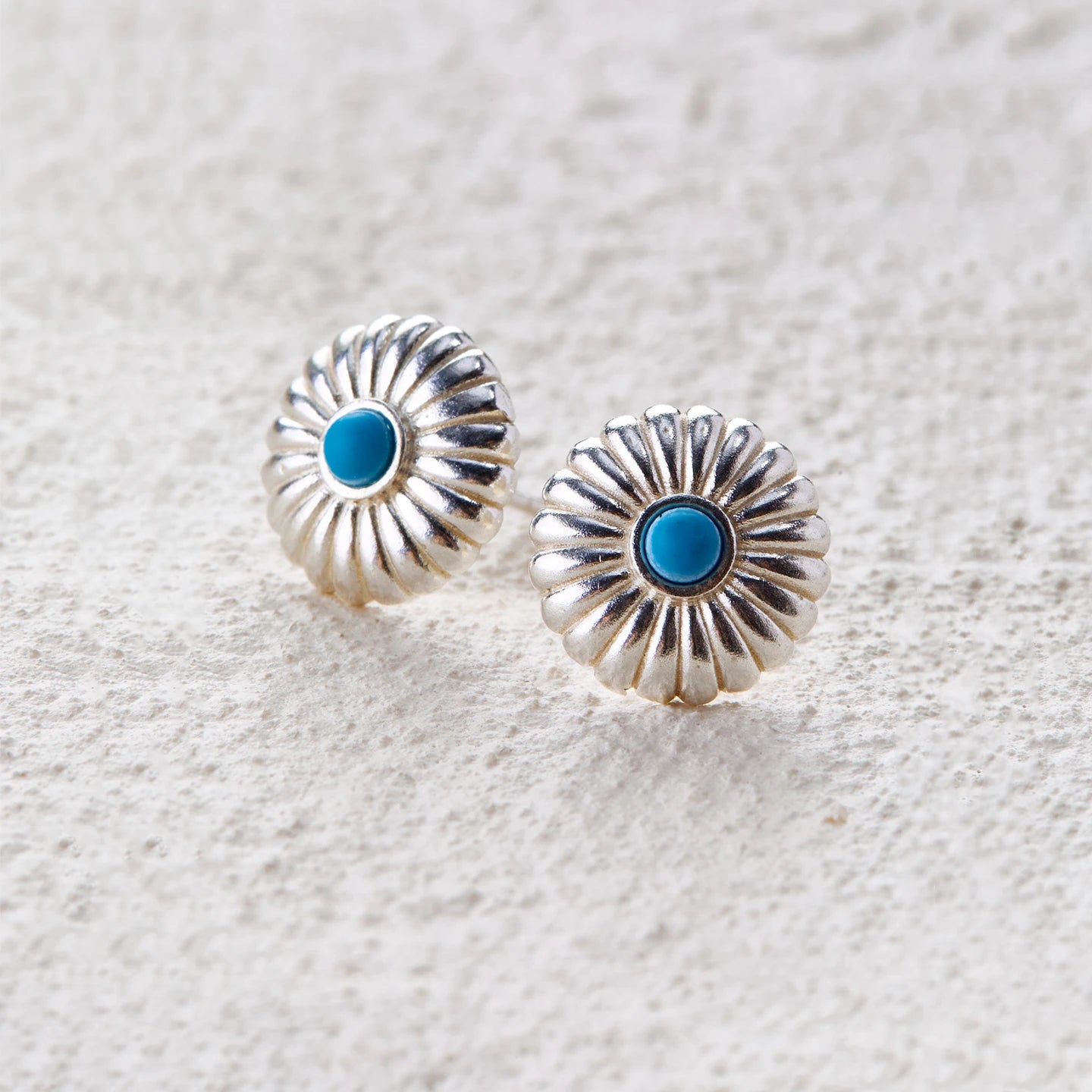 Round silver earrings inspired by sun blossoms, featuring vivid turquoise at the center