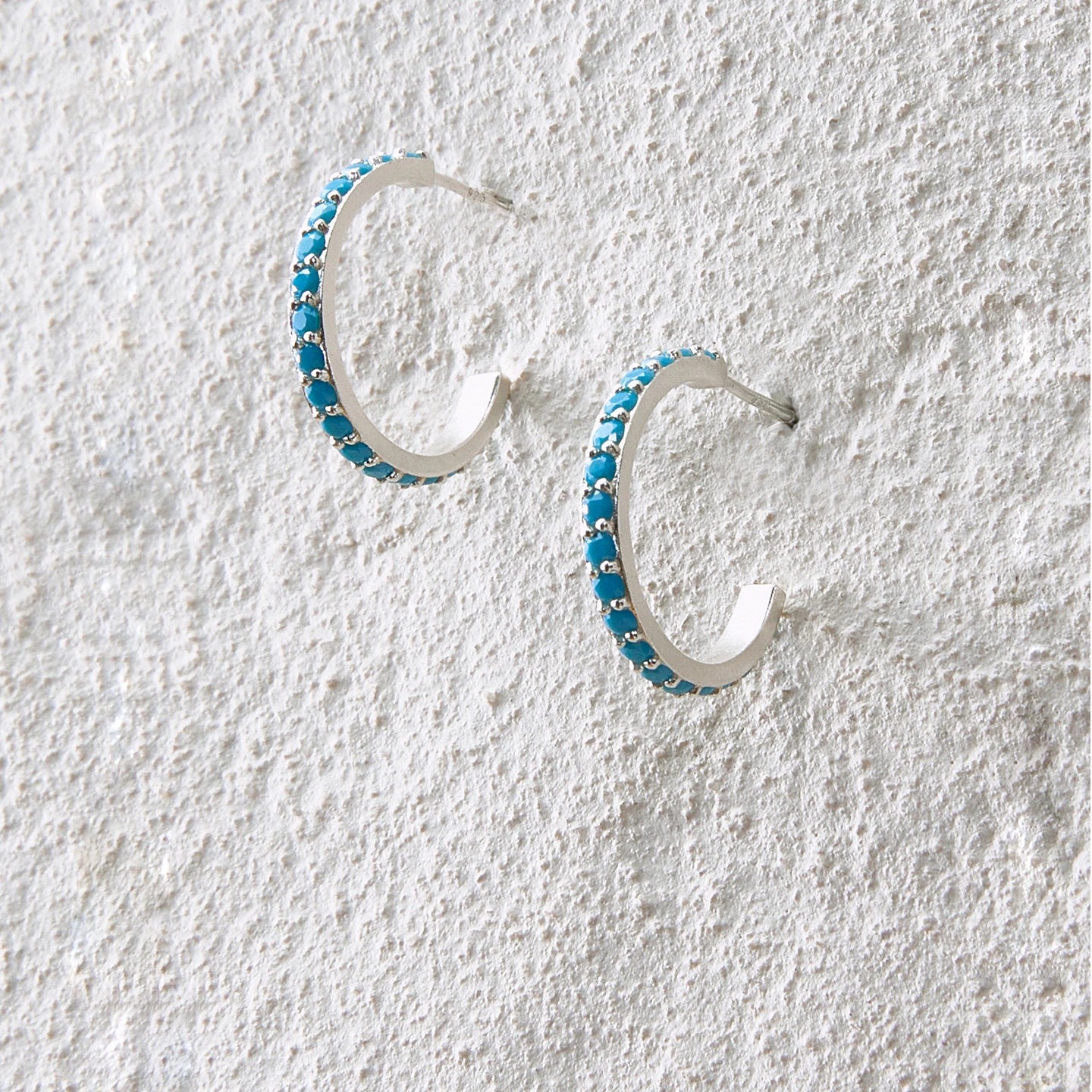 Minimalist hoop earrings with turquoise stones set along a silver arc