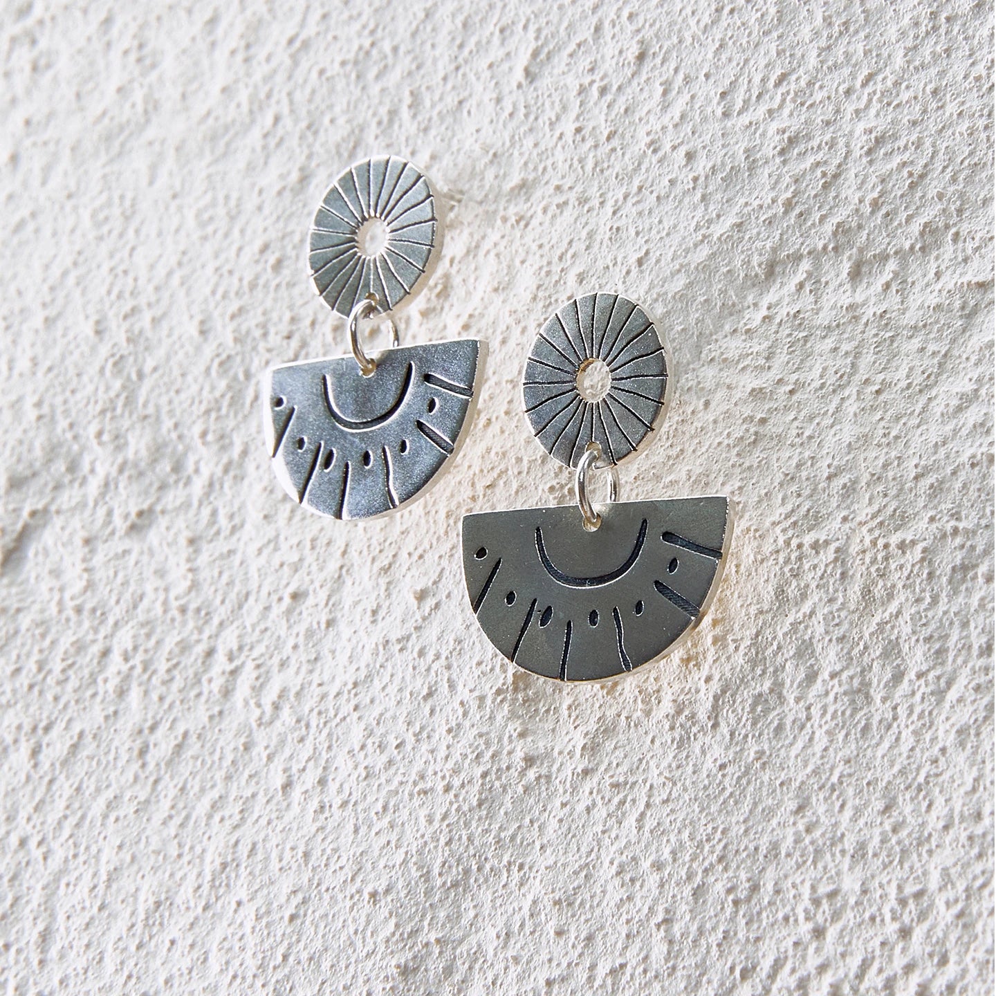 Silver drop earrings with sunburst engravings and half-circle sun motifs