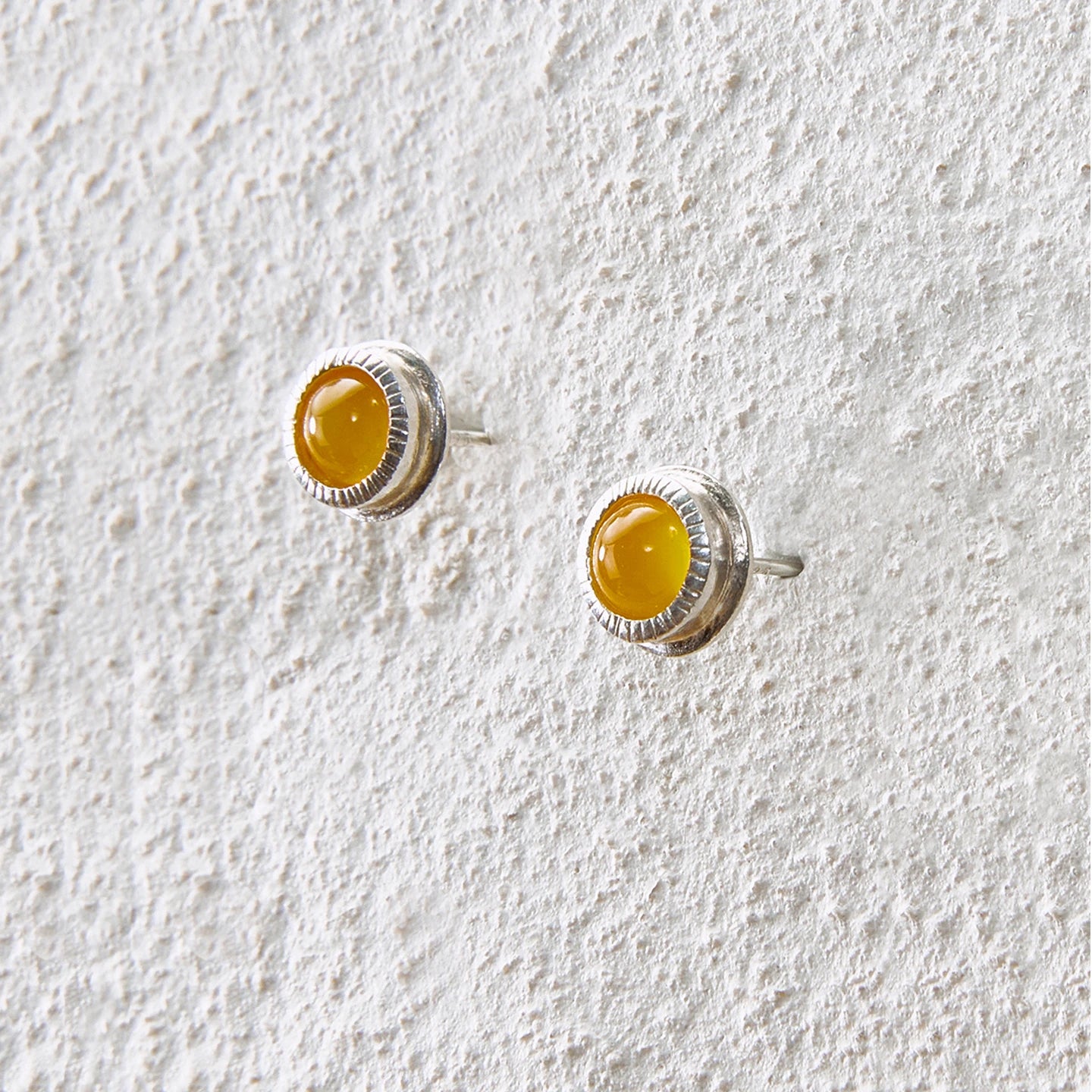 Round yellow agate stud earrings with detailed silver bezel setting