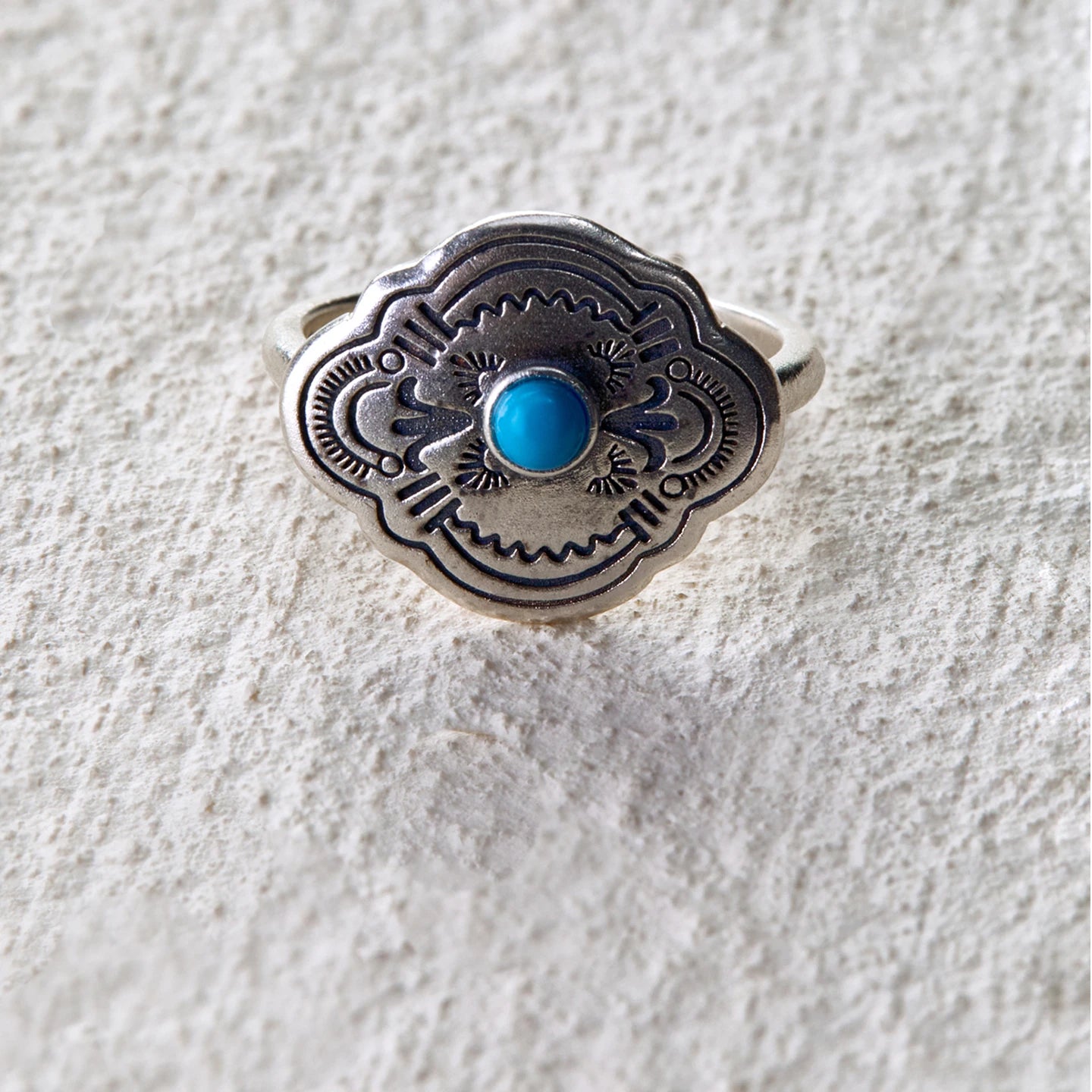 Silver ring engraved with tribal totem patterns, centered with a turquoise stone