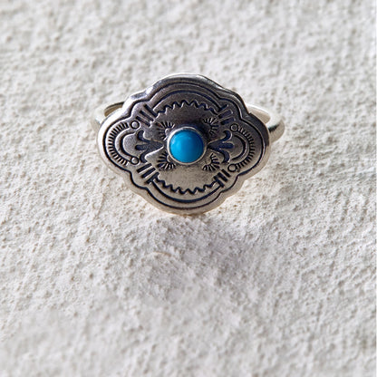 Silver ring engraved with tribal totem patterns, centered with a turquoise stone