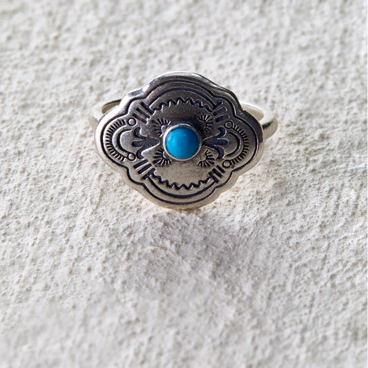 Silver ring engraved with tribal totem patterns, centered with a turquoise stone